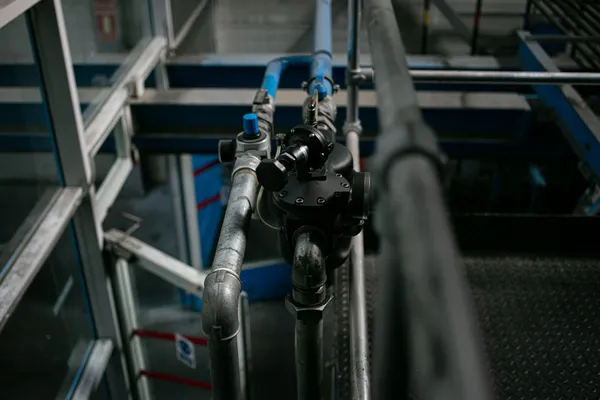 Industrial pipework and valve assemblies beside a metal service walkway